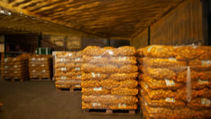 Stapel von Kartoffelnetzen auf Paletten in einem Lagerraum.