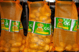 Drei Säcke mit Kartoffeln in orangefarbenen Netzen, mit grünen Etiketten versehen.
